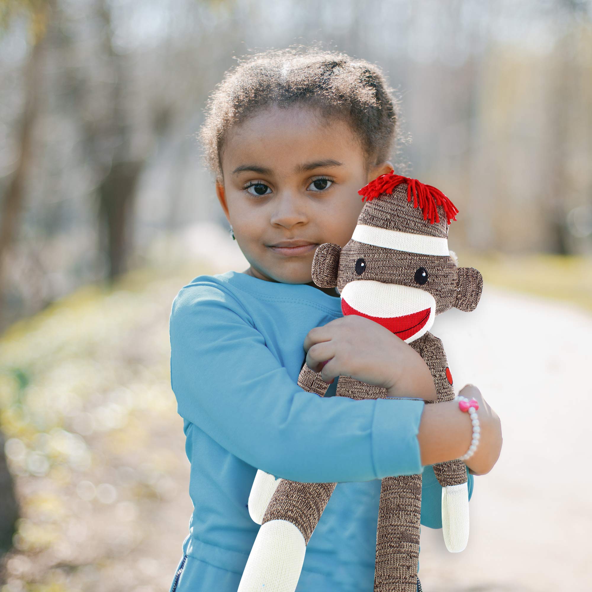 A girl holding 6-inch brown Sock Monkey, huggable vintage toy with soft plush fabric by Plushland