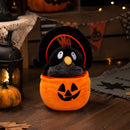 Halloween crow plush toy beside a pumpkin lantern and bat decorations