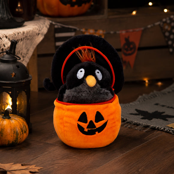 Halloween crow plush toy beside a pumpkin lantern and bat decorations