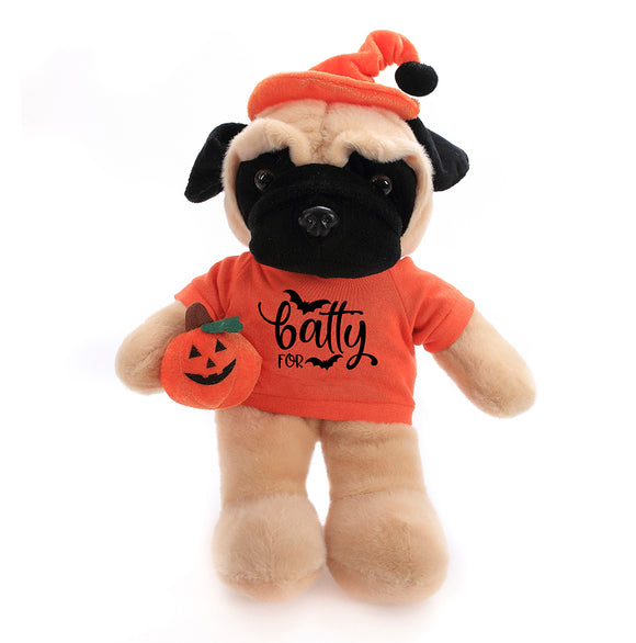 Halloween Pug Plush Floppy 12" in a front-facing pose wearing a Halloween t-shirt and hat while holding a pumpkin treat bag